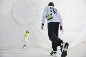 Hombre y mujer caminan dentro de un globo aerostático vestidos con prendas y deportivas urbanas